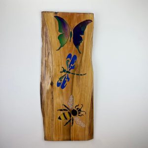 wooden plank with a butterfly dragonfly and bee stencil in mixed colours
